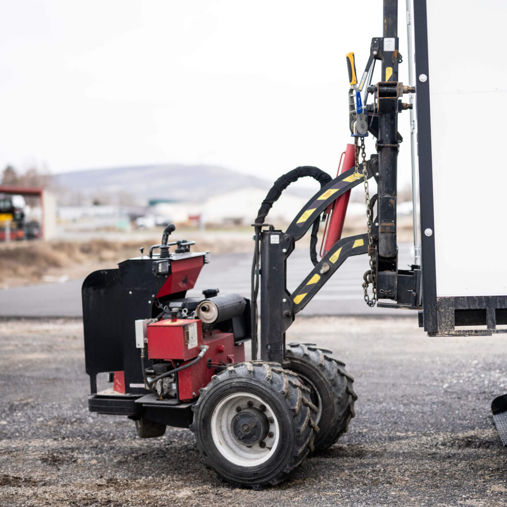 Small loader attached to a trailer.